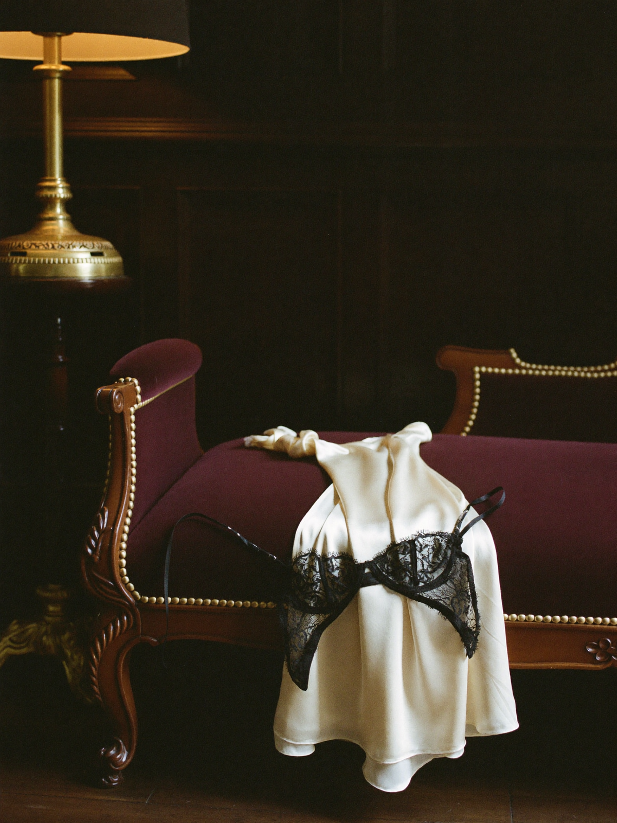 Black lace and ivory silk lingerie draped over a burgundy velvet chaise